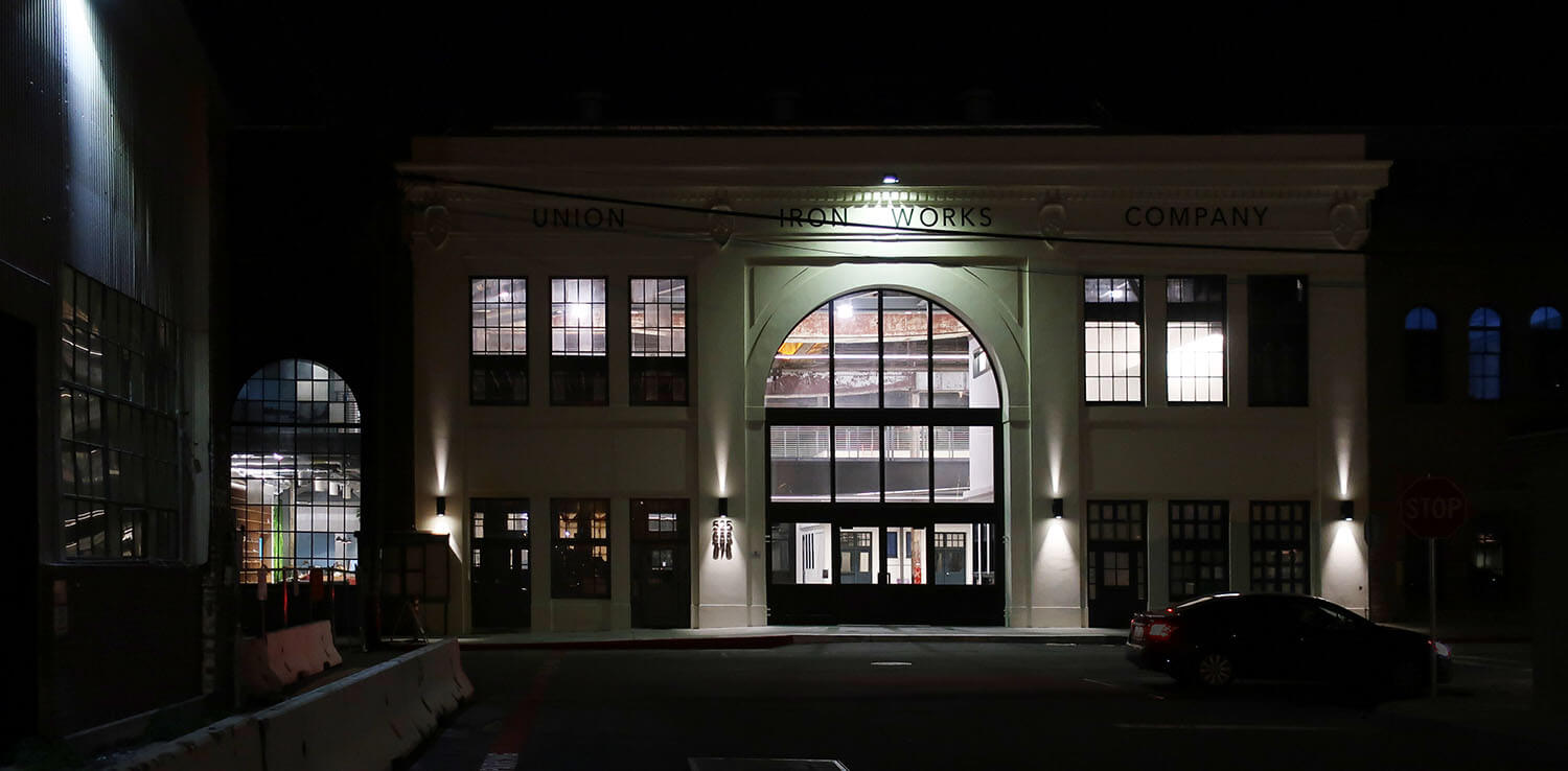 Exterior night view of historic building facade with dramatic downlighting