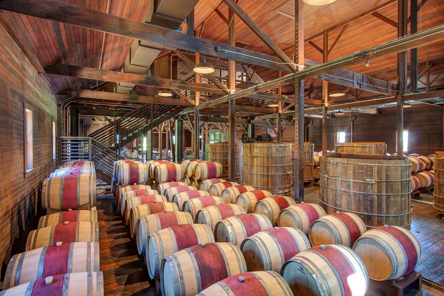 Interior view of wine barrel storage room with wine-stained barrels and other winery equipment