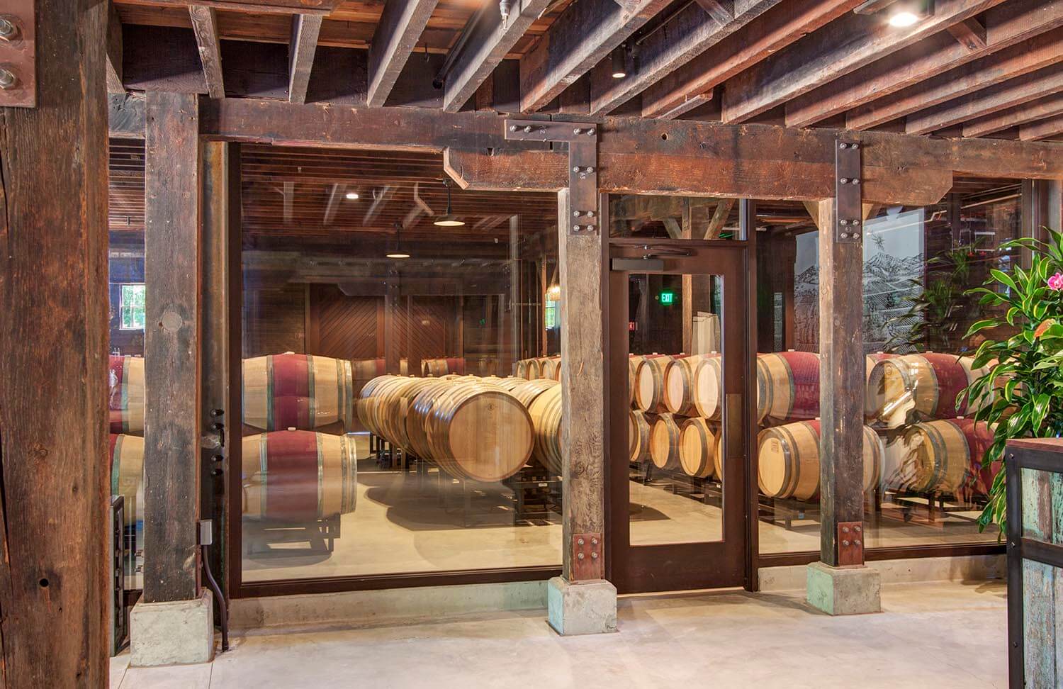 Interior view of wine barrel storage room behind glass walls and closed, glass door